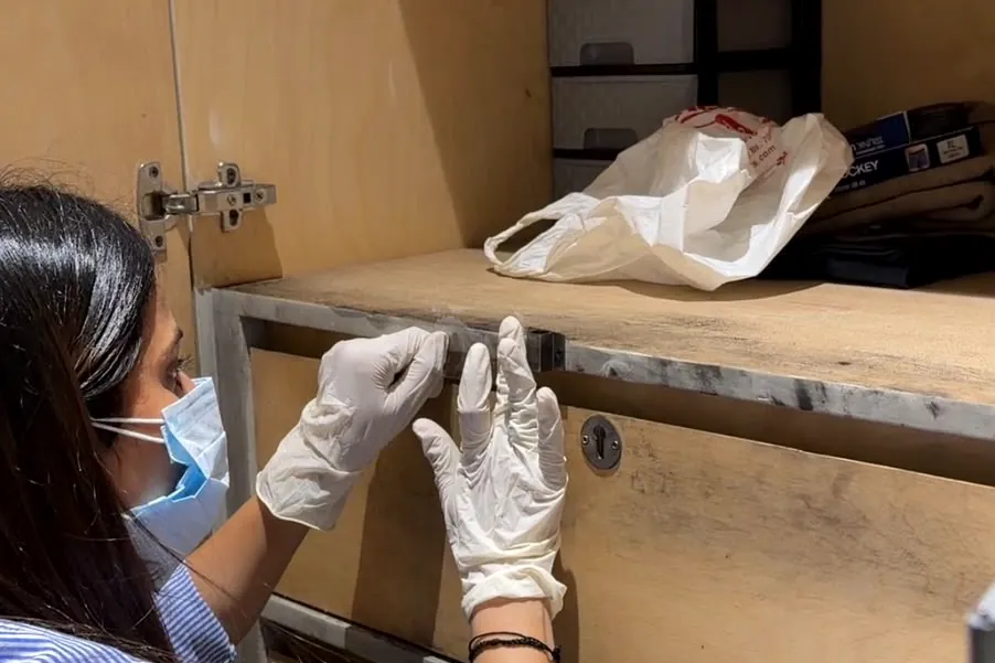 Forensic examiner processing a locked drawer for evidence